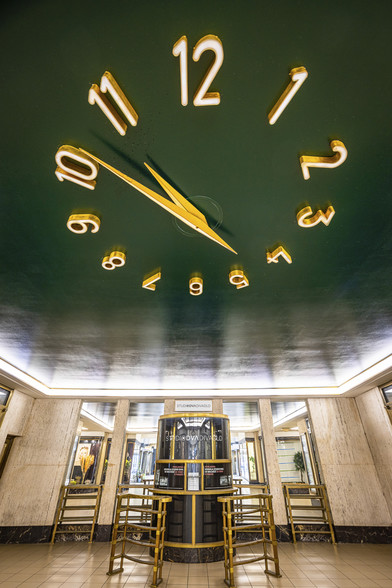 Look up towards the ceiling of the Fénix Passage in Prague, ornated with a giant, modern-style, golden clock on a dark green background. This passage, situate on the Wenceslas Square, was designed by Josef Gočár and Bedřich Ehrmann, and is one of the earliest representatives of functionalist constructivism.