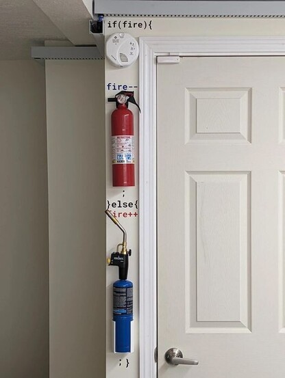 The picture is of the left doorpost which has the following items attached in a vertical line from top to bottom: a smoke alarm, a fire extinguisher, and a gas blowtorch.

Text has been added: 
If (fire){
(fire alarm goes here)
fire--
(fire extinguisher goes here)
;
}else{
fire++
(gas blowtorch goes here)
; }
