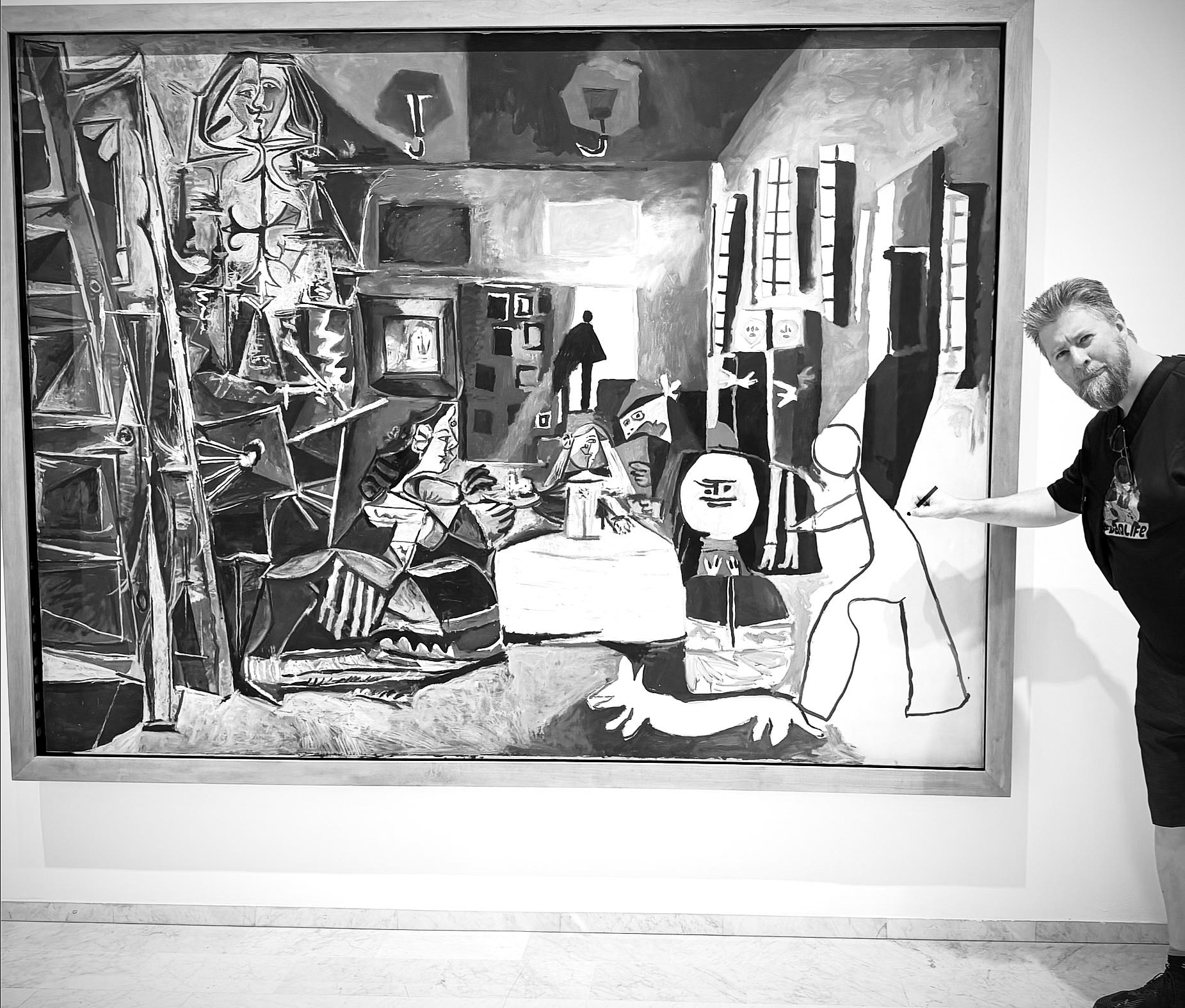A man poses next to a large black-and-white Picasso painting in a gallery, pointing towards its right side. The artwork features abstract, cubist-style figures, geometric patterns, and a dog